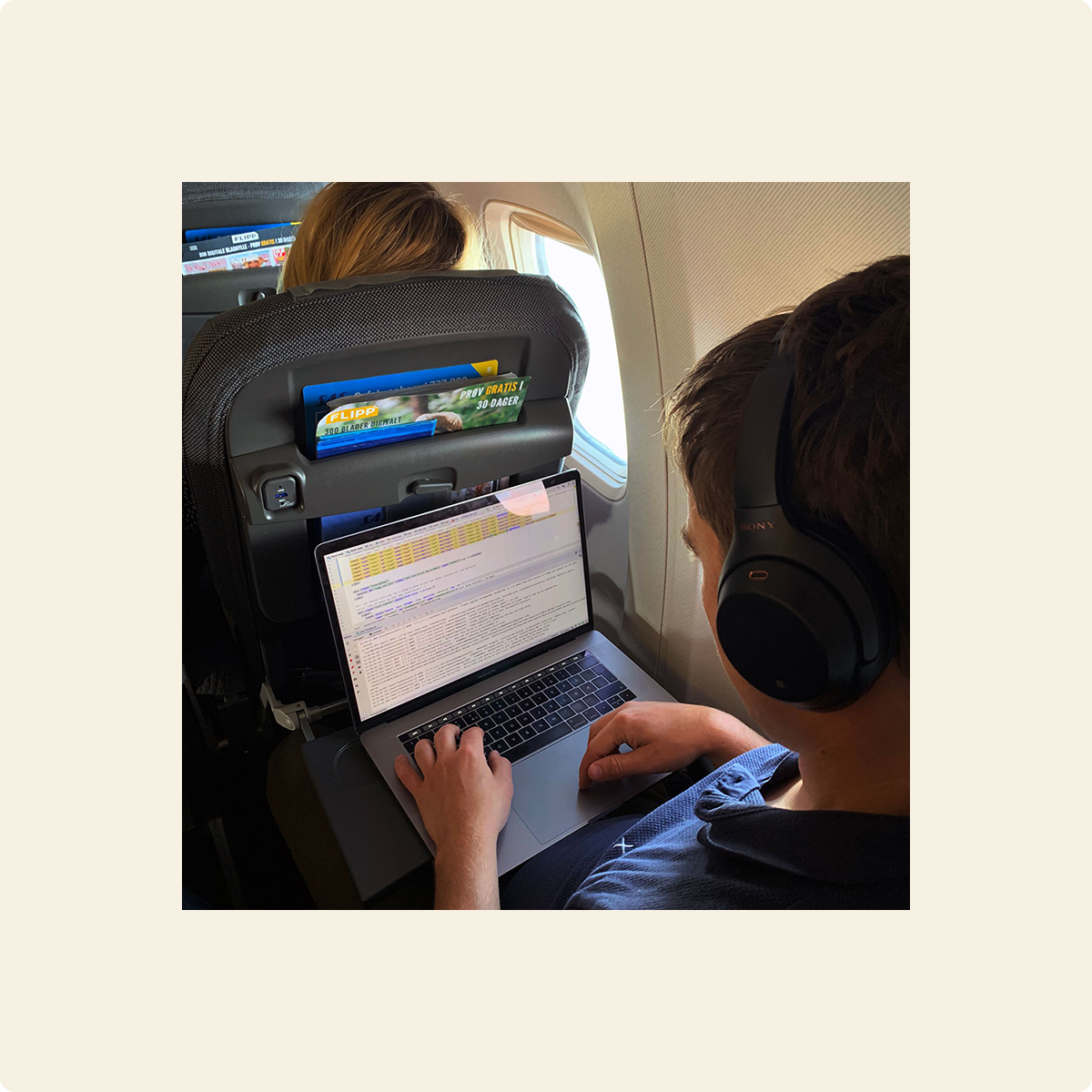 Fotografi av person på fly som sitter med datamaskin i fanget