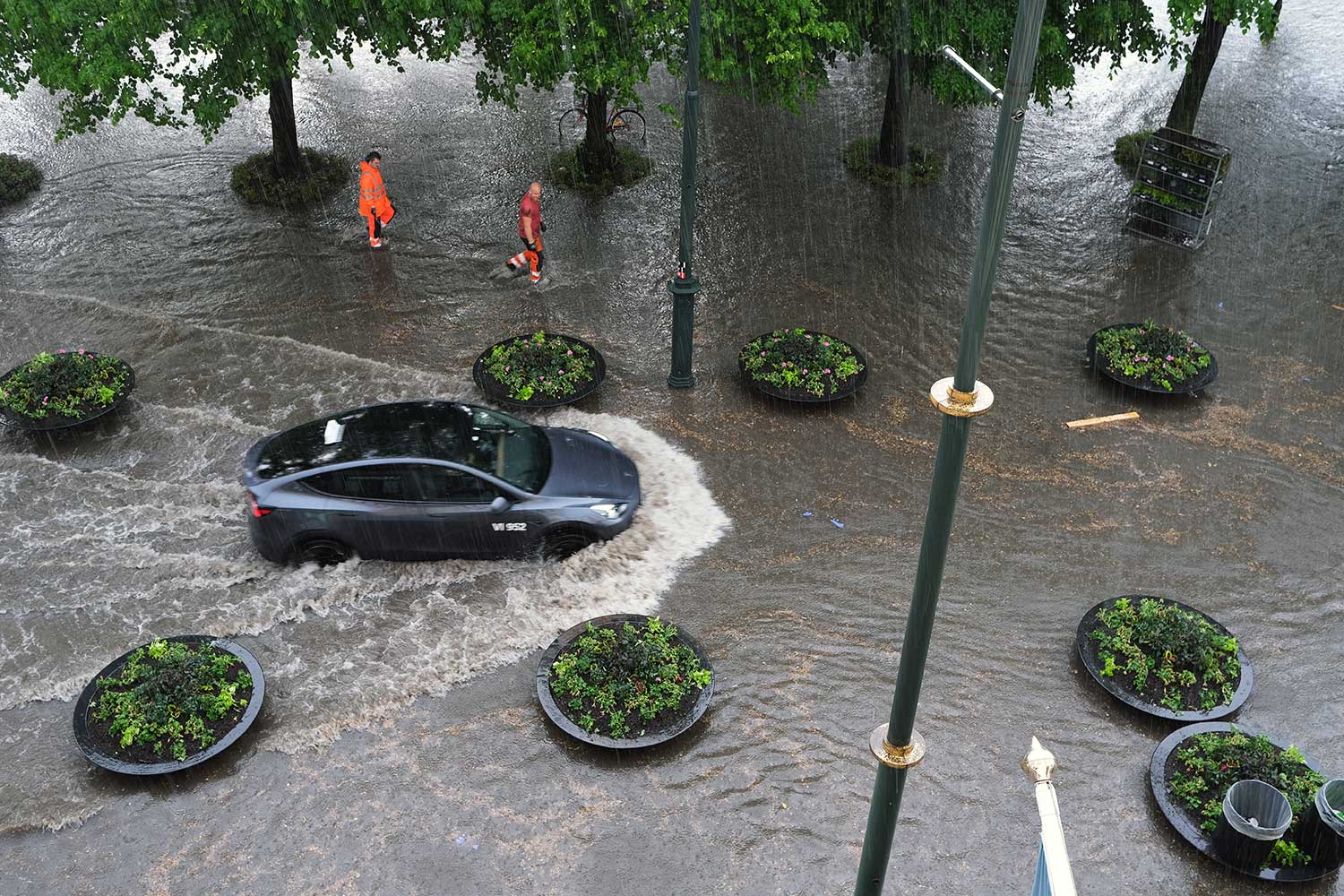 Fotografi av bil som kjører gjennom en oversvømmet gate.