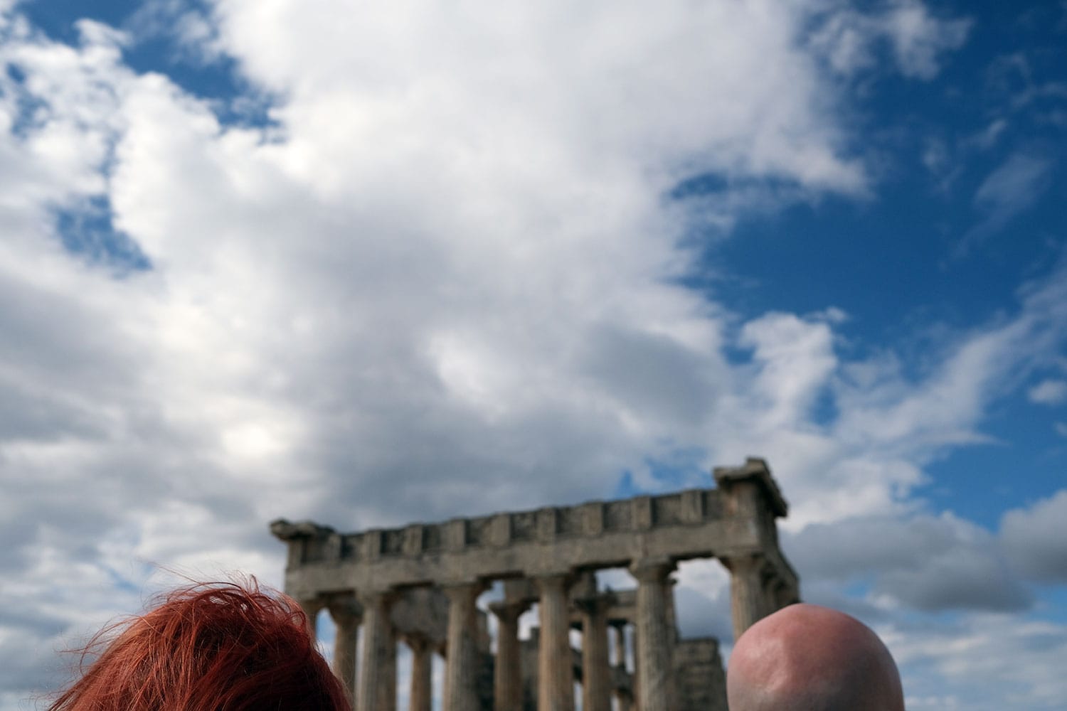 Fotografi av to personer som står foran en ruin av et tempel i Hellas.