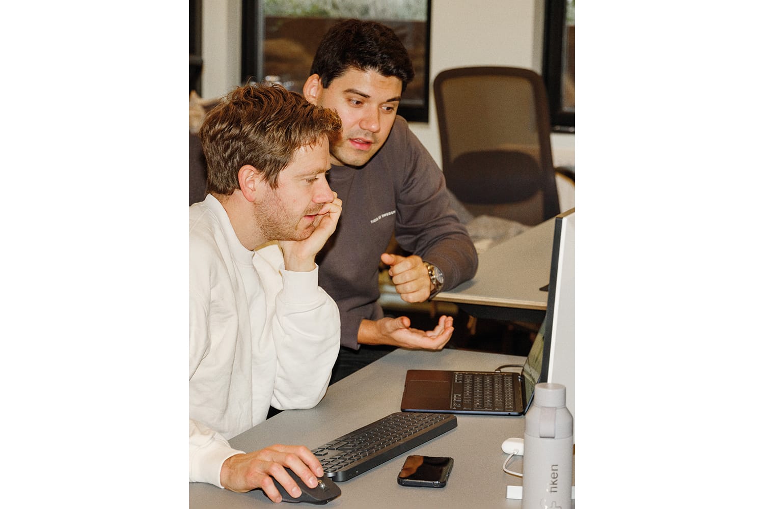 Fotografi av to Fiken-ansatte som jobber på kundestøtte